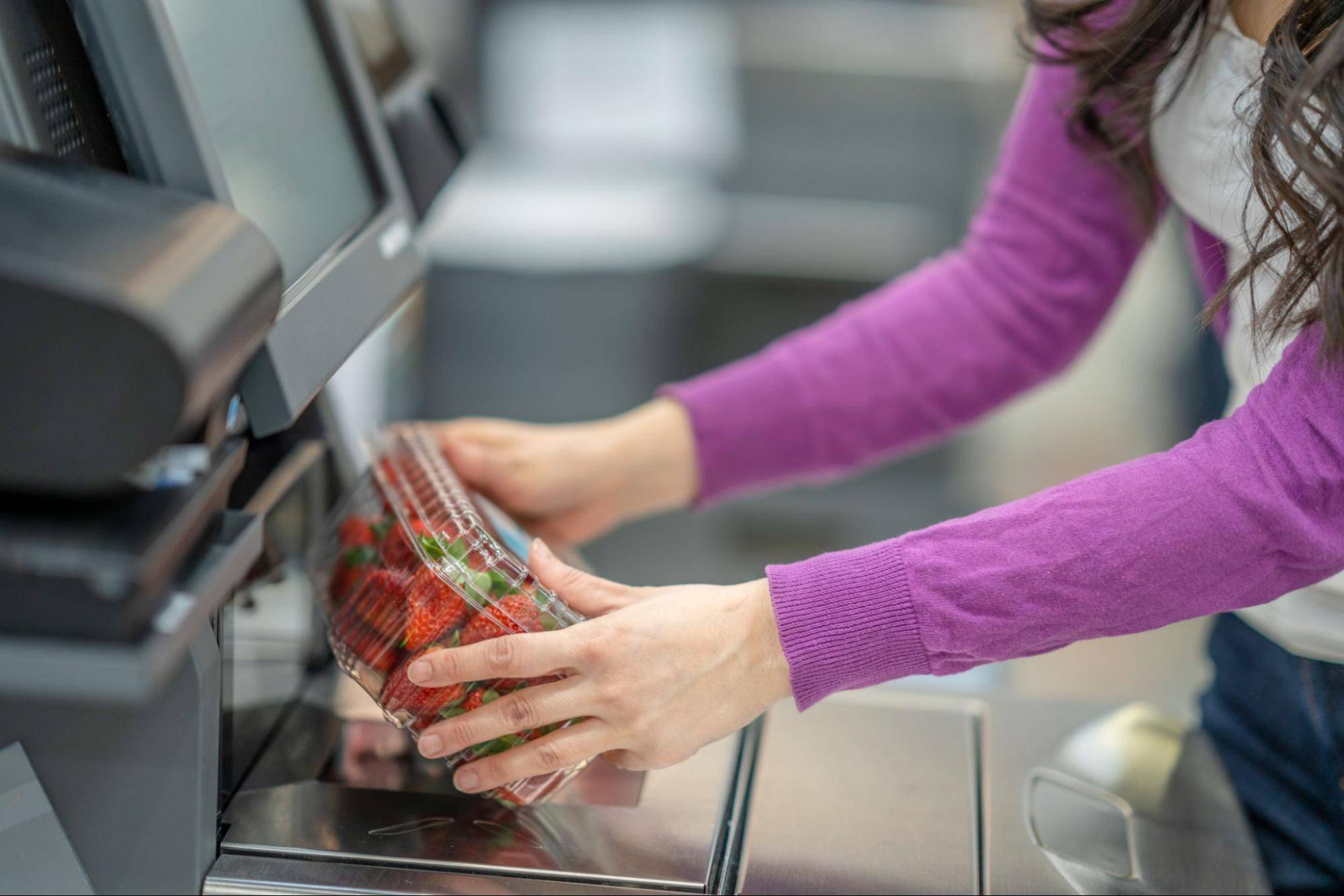 woman scanning strawberries at grocery store